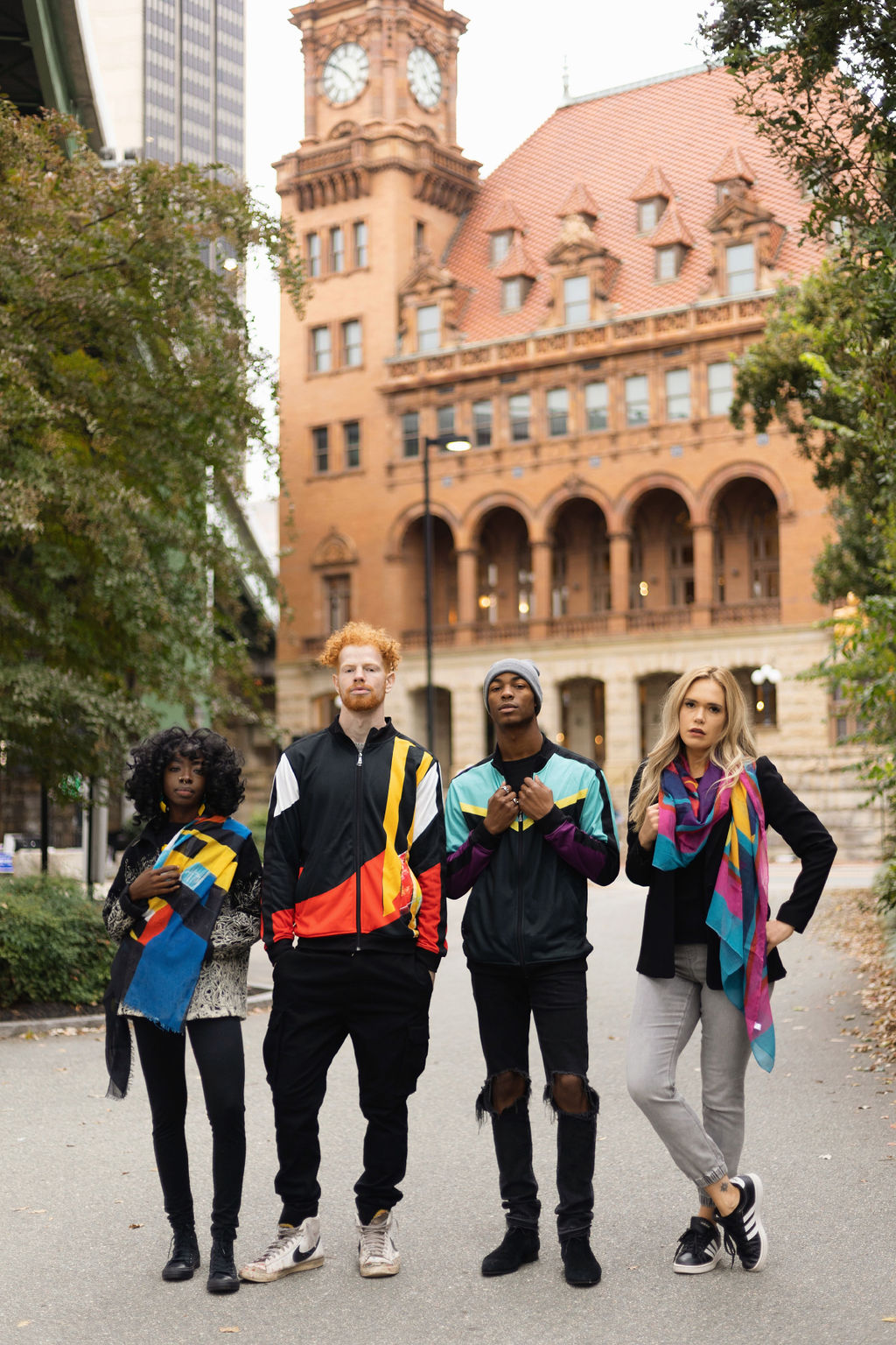 Four people standing in front of a large building with a clock tower.